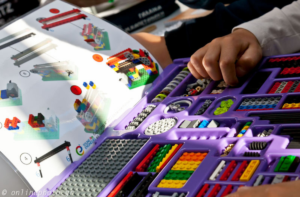 Kids hand grabbing Lego pieces from a Young Engineers play box