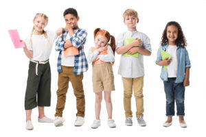 multiethnic children holding textbooks and smiling at camera isolated